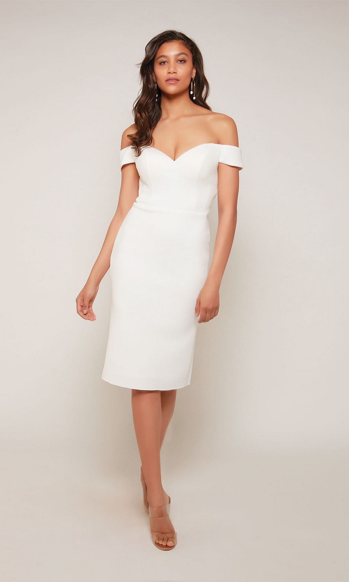 A woman wears the Alyce 70047 knee-length semi-formal dress in diamond white with nude heels, standing against a plain background.